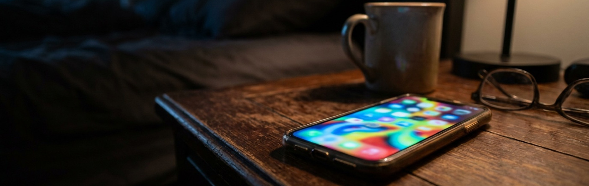 Een smartphone met een fel oplichtend scherm in een donkere kamer, symbool voor laat schermgebruik door pubers.