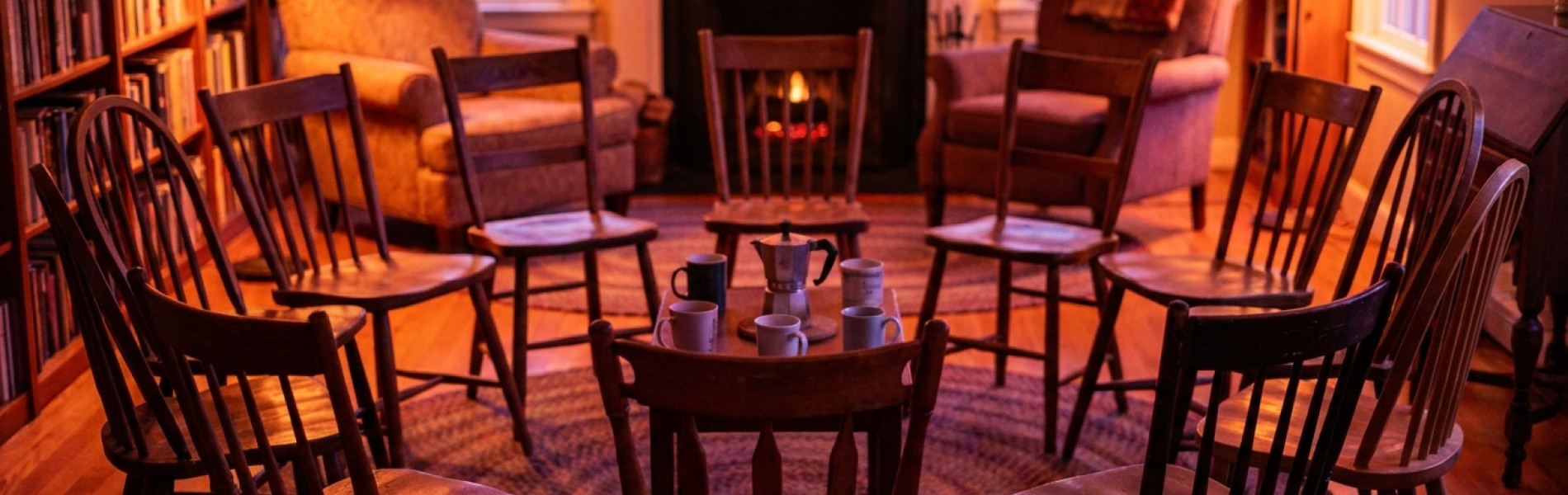 Een kring lege houten stoelen in een warm verlichte ruimte, klaargezet voor een ouderavond over opvoeden.