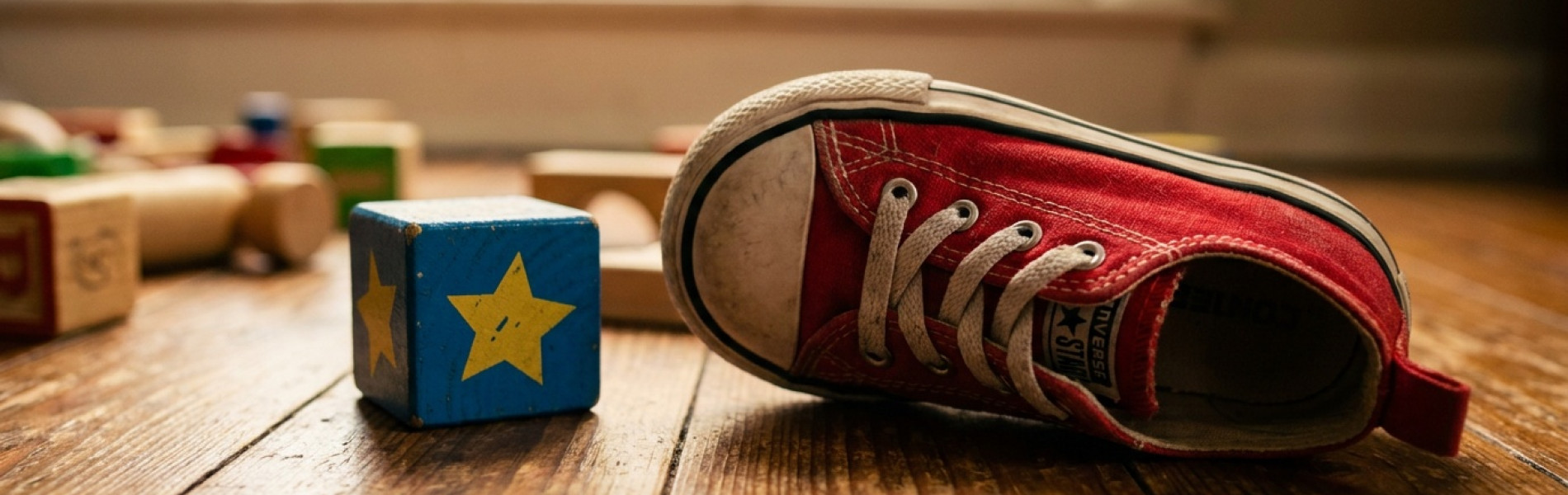 Een klein kinderschoentje en een los blokje liggen verspreid op een houten vloer, symbool voor de koppigheidsfase van een peuter.